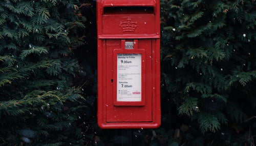 Red Christmas postbox in a winter bush