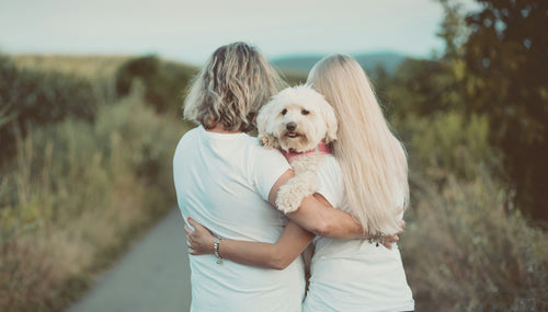 mother and daughter hugging on a lane with a white dog in their arms