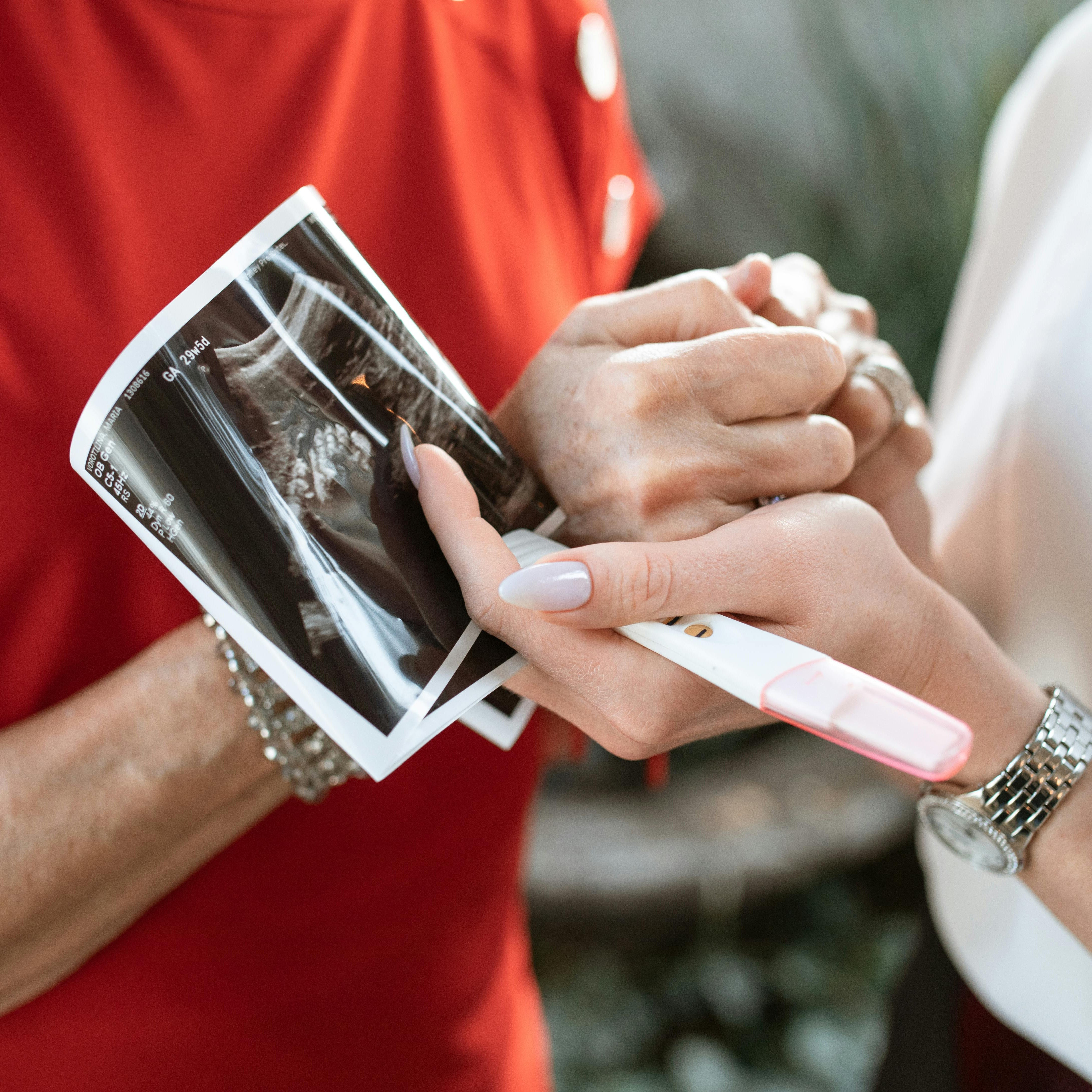 A mother and grandmother holding hands with a pregnancy test. Mum to be gifts.