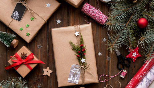 brown paper christmas presents with christmas tree sprigs and red baubles scattered around