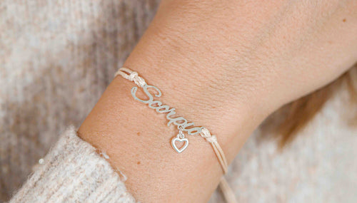 A beige jumper with a woman and a bracelet. The bracelet has a script font reading 'Scorpio'