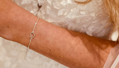 Woman in a wedding dress wearing a silver heart charm bracelet