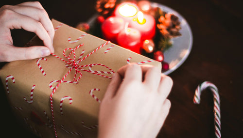 women's hands tying a string bow on a Christmas present