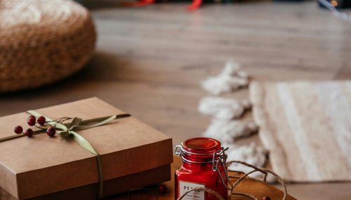 a wooden floor with wooden coffee table and gifts wrapped in brown paper and a red candle