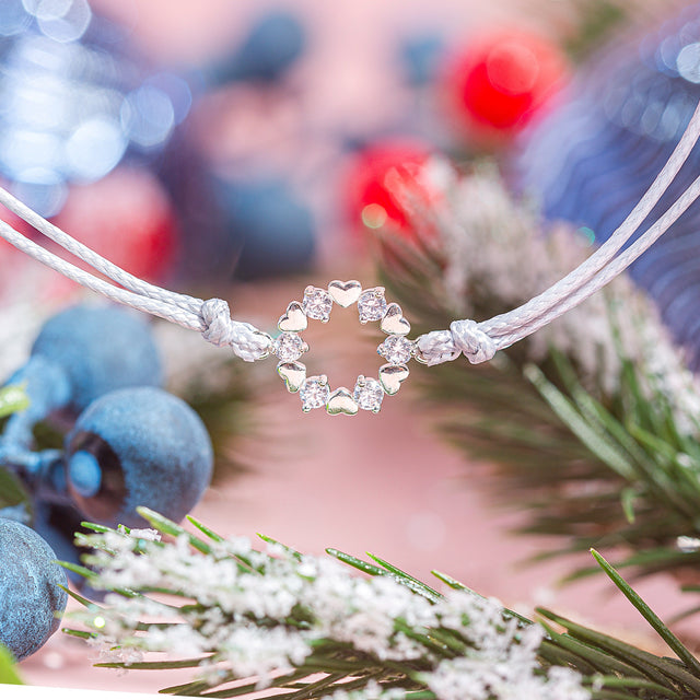Festive background with a friendship bracelet and a wreath charm.