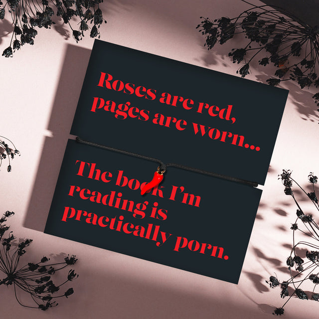 A mystical pink background with black stems and a book lover gift. The poem card is aimed at spicy book lovers with a black chilli bracelet charm.
