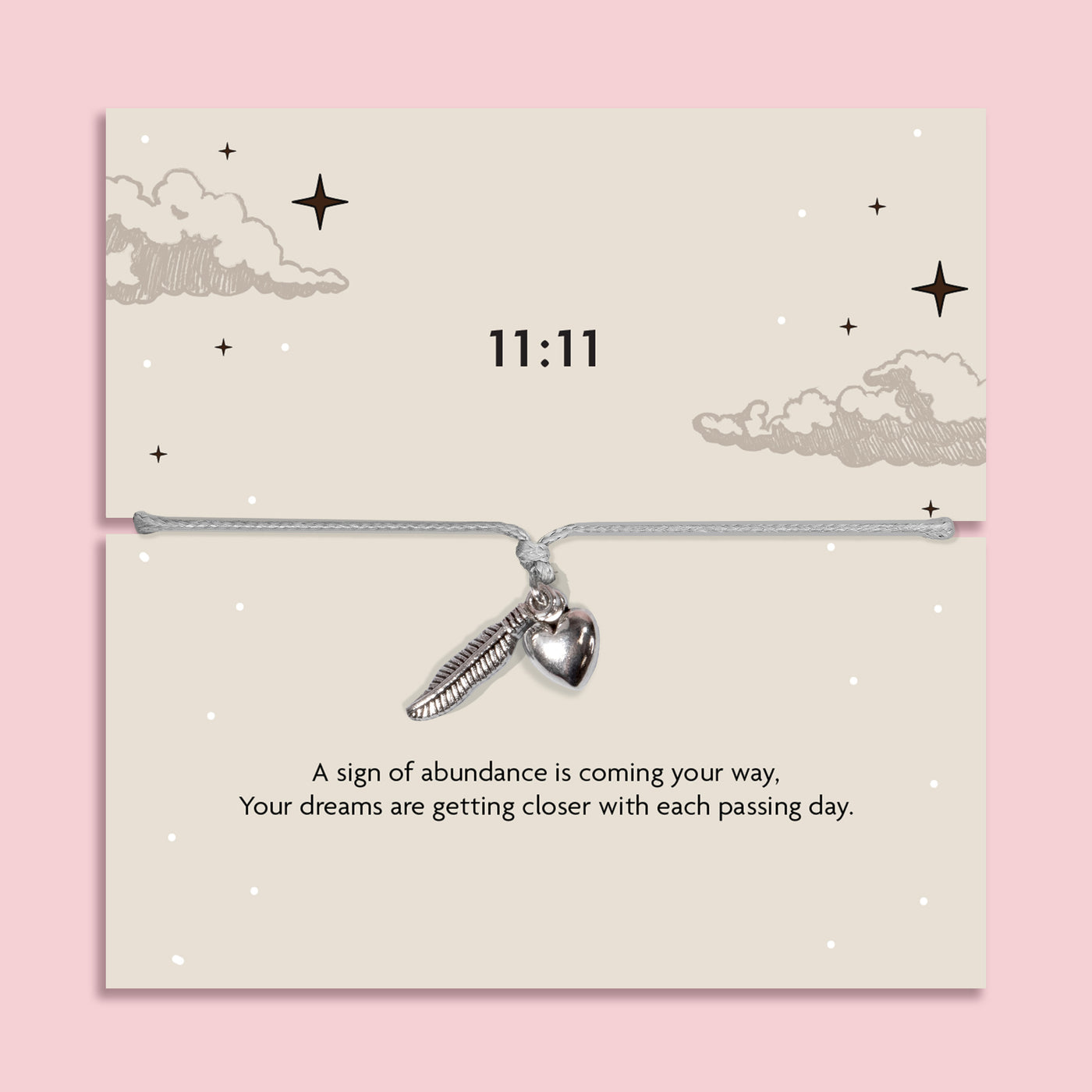 White adjustable 11:11 angel number bracelet with silver-tone feather and heart charms, displayed on a celestial sentiment card with a manifestation and abundance message.