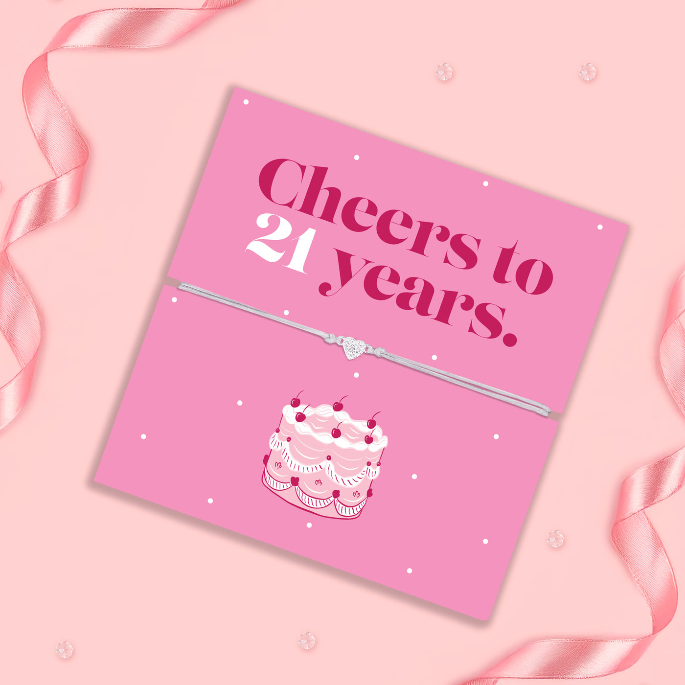 Pink card with 'Cheers to 21 years' text and cake illustration on a pink background with ribbons.