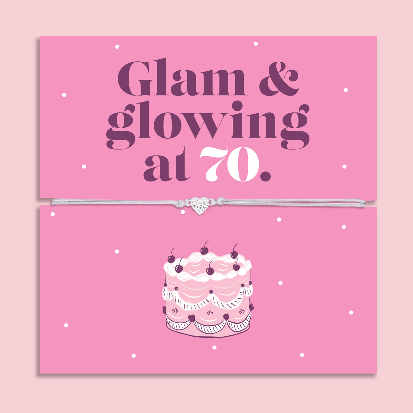 Pink 70th birthday gift card with the text “Glam & glowing at 70” in bold purple and white lettering, featuring a silver and grey adjustable heart charm bracelet across the centre and an illustrated birthday cake below.