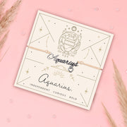 Aquarius-themed bracelet on a matching card with decorative elements on a pink background. Star sign jewellery for women.
