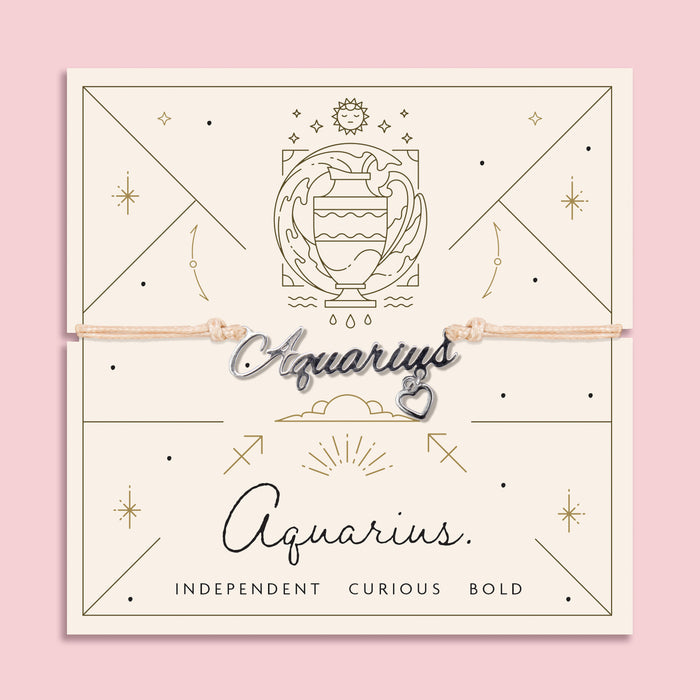 Adjustable peach cord bracelet with a silver 'Aquarius' charm and dangling heart pendant, displayed on a zodiac-themed card with a water bearer illustration and traits reading "Independent, Curious, Bold".