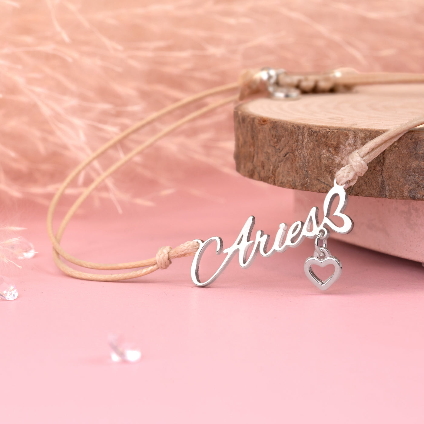 Meaningful bracelet with 'Aries' and heart charm on a pink background. A friendship bracelet perfect for an Aries woman.
