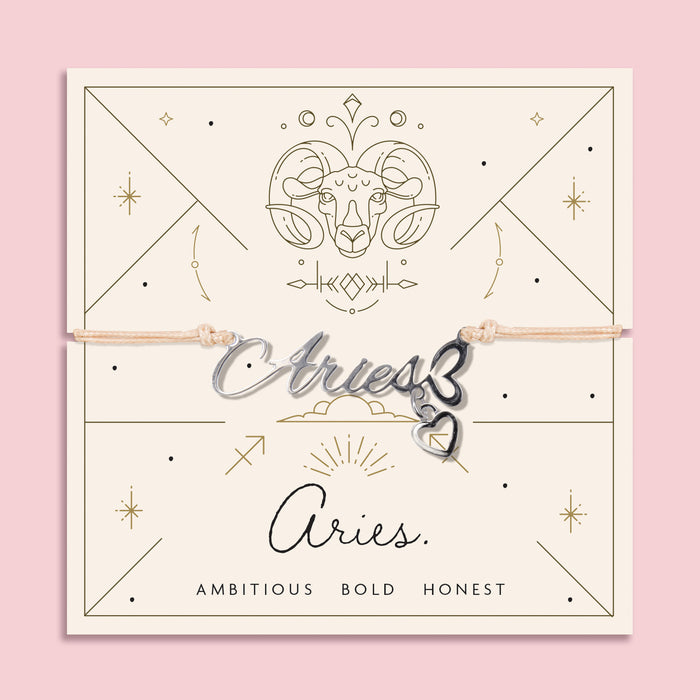 Peach cord bracelet featuring a silver 'Aries' script charm with heart pendant, presented on a zodiac card with ram illustration and personality traits "Ambitious, Bold, Honest".