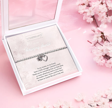 Silver beaded bracelet with heart and flower charms, displayed in a white gift box alongside a card titled 