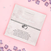 A silver beaded bracelet with a heart and flower charm displayed on a card reading "To my Amazing Auntie" from Letterbox Love, set against a soft pink background with decorative flowers and gemstones. The bracelet is presented with a sentimental message, perfect for gifting to an auntie.