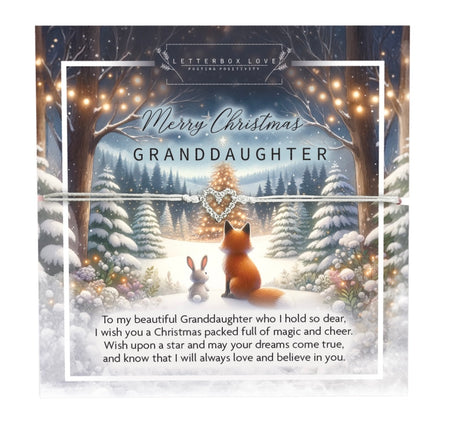 A delicate Christmas bracelet designed for a granddaughter, featuring a sparkling heart charm on a thin white cord. The bracelet is displayed on a festive card with a charming winter scene, depicting a fox and a rabbit sitting together in a snowy forest under twinkling fairy lights. The card includes the message: 