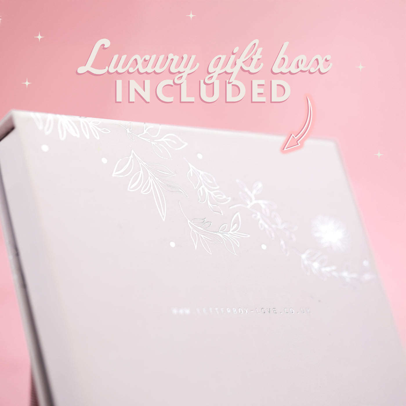 A pale pink background with text that reads 'luxury gift box included' and an arrow pointing to the box. The box is white with floral silver details.
