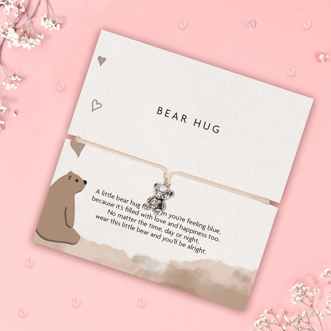 Card with a bear hug charm and text on a pink background
