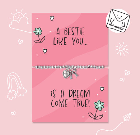 A silver beaded bracelet with a heart and key charm is displayed on a pink gift card that reads 'A BESTIE LIKE YOU.