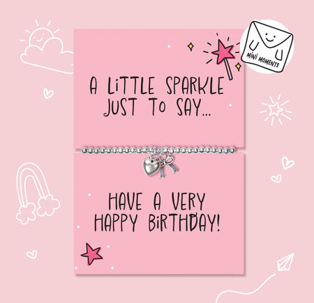 A silver charm bracelet with a heart and key pendant displayed on a pink birthday card that reads 'A LITTLE SPARKLE JUST TO SAY.