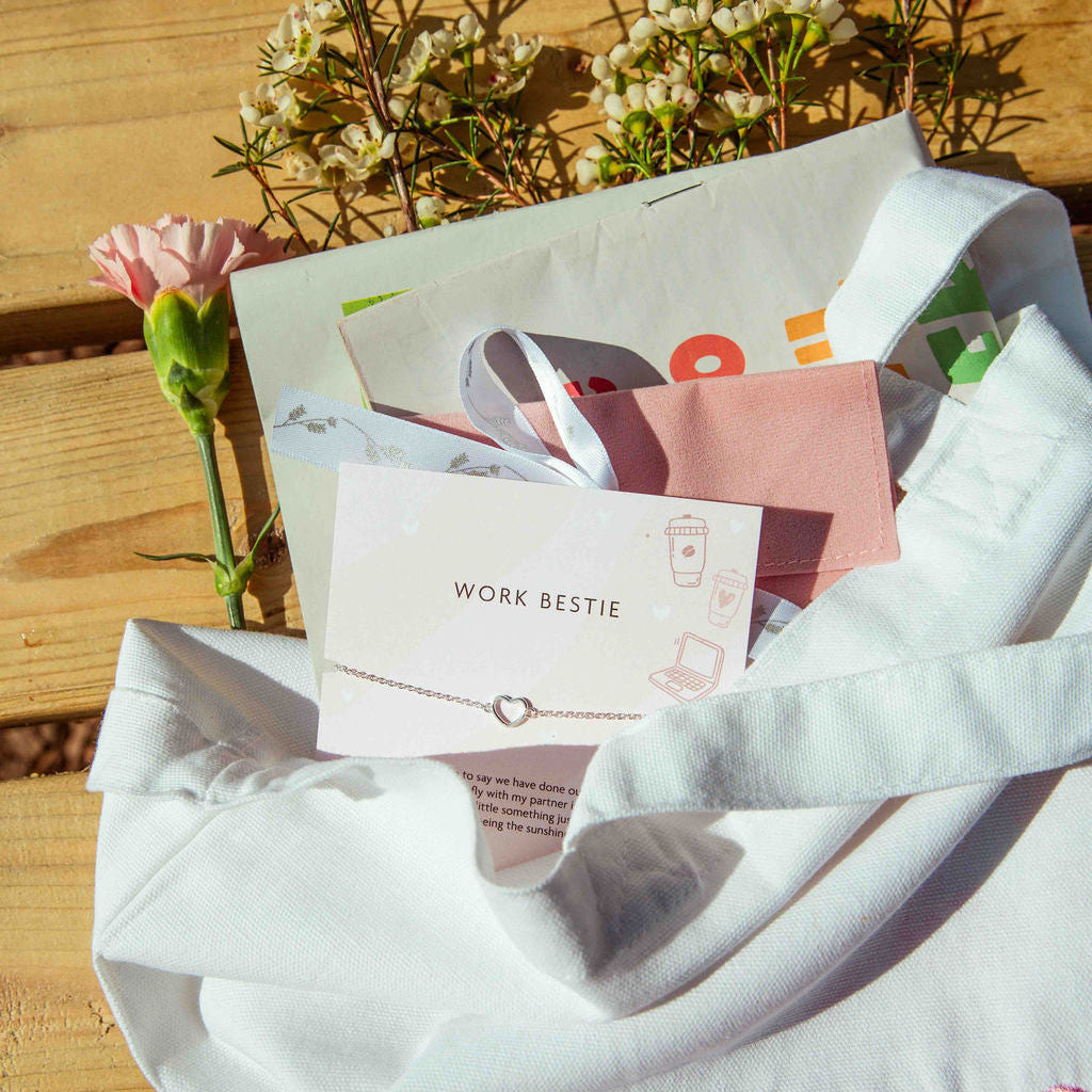 Letterbox Love packaging with a Work Bestie Bracelet and pink flower on a wooden surface