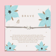 Silver bracelet with a butterfly charm presented on a white 'BRAVE' card decorated with teal flowers and a touching message about strength and perseverance.