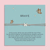 Grey cord bracelet with a silver butterfly charm, displayed on a teal card with butterflies and the word 'Brave'. The card features an inspirational message about strength, resilience, and courage. An empowering gift from Letterbox Love.
