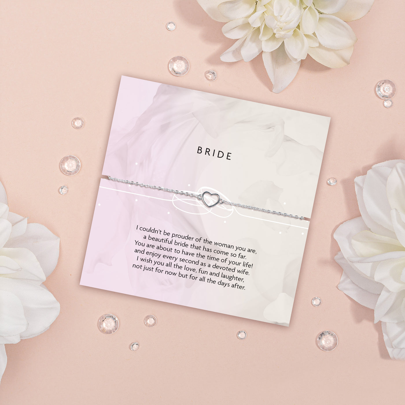 Bride bracelet with sentimental message card on a decorative background with flowers and pearls. A thoughtful silver heart bracelet for a bride.