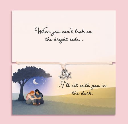 Adjustable friendship bracelet with moon and star charms on a cord, presented on a sentimental card reading “When you can’t look on the bright side… I’ll sit with you in the dark,” a meaningful support and encouragement gift for a friend.