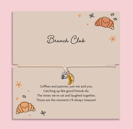 Brunch club friendship bracelet with gold croissant charm and silver heart on adjustable cord, displayed on brunch themed gift card
