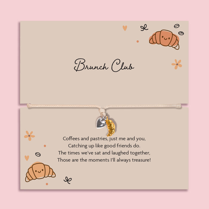 Brunch club friendship bracelet with gold croissant charm and silver heart on adjustable cord, displayed on brunch themed gift card