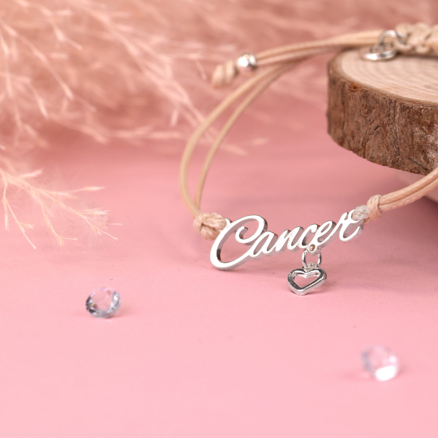 Bracelet with 'Cancer' charm on a pink background. Star sign jewellery under £20, zodiac bracelet for a birthday gift