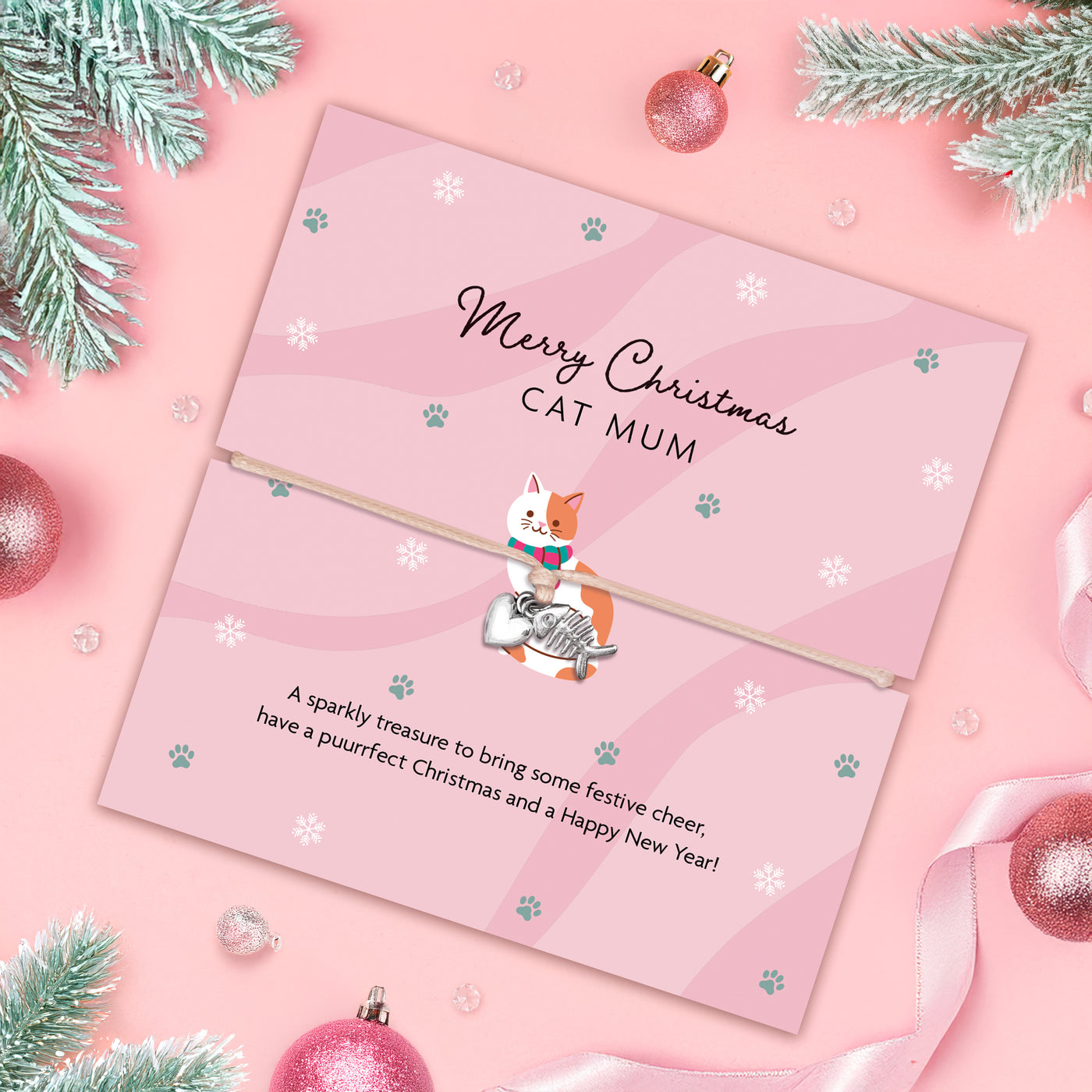Pink Christmas card with a cat illustration and festive decorations on a pink background. Animal lover bracelet with fish bone and heart charms.