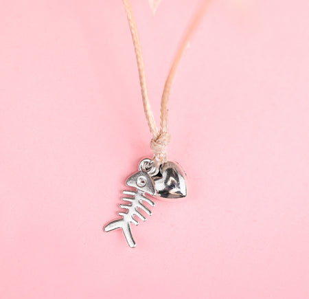 Christmas bracelet with silver fish and heart charm. A cute gift for a cat mum for Xmas. Set on a pink background.