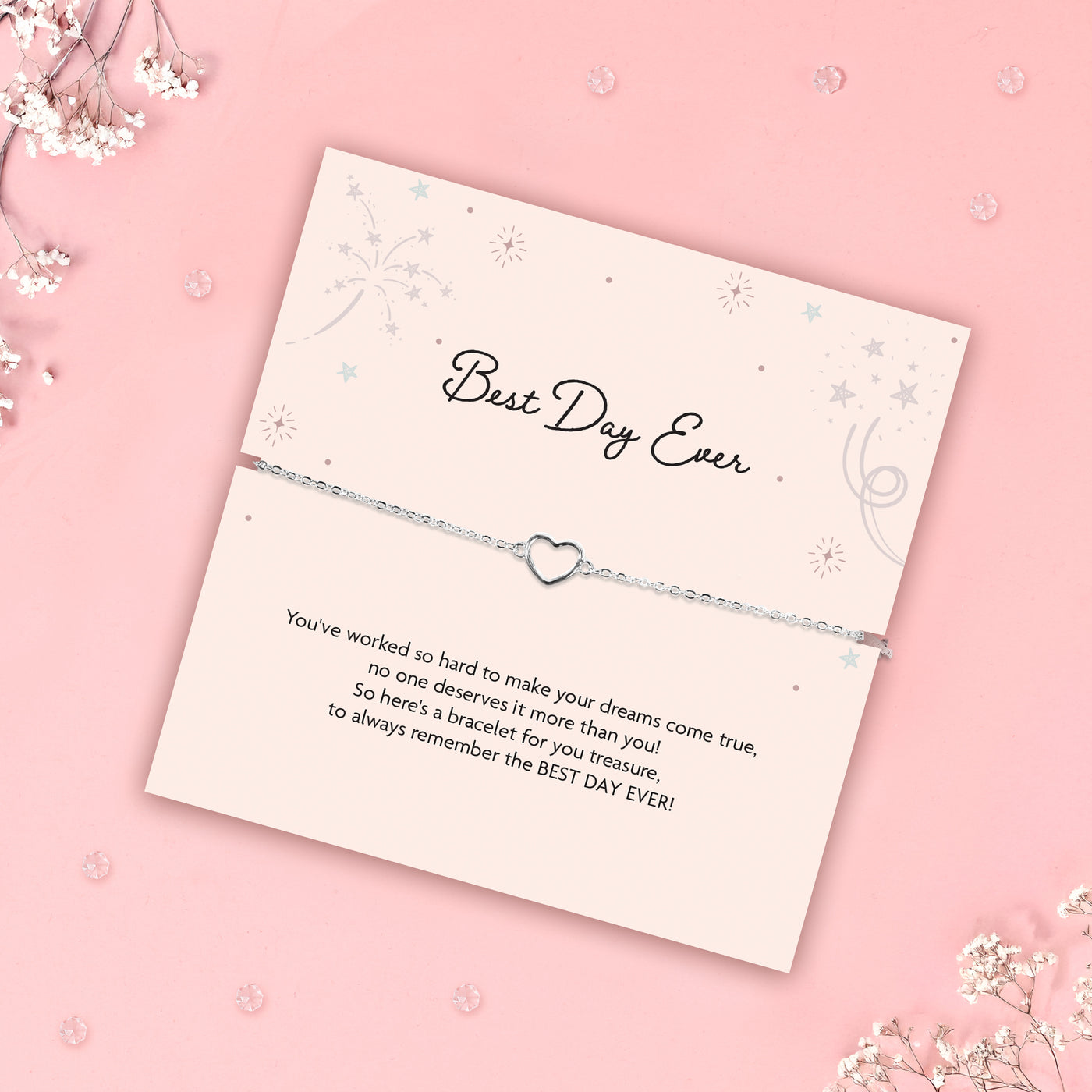 Bracelet with heart charm on a 'Best Day Ever' card on a pink background