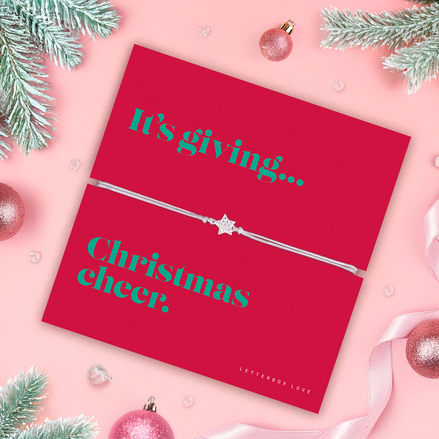Pink background with Christmas decorations, the focal point is a poem card with a friendship star bracelet, a perfect gift for a friend this Christmas