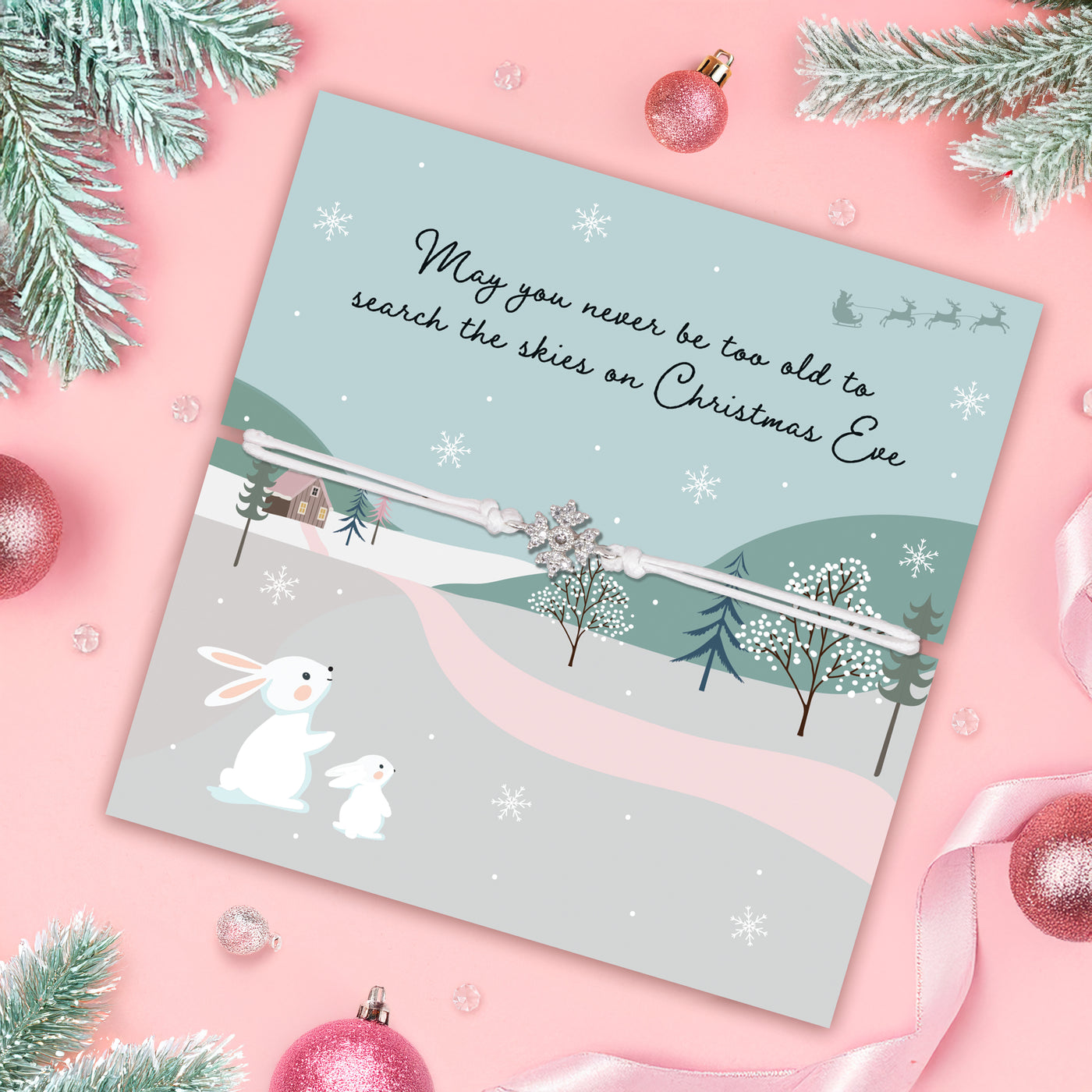 Christmas-themed poem card with a friendship bracelet on a pink background with Christmas decorations. An affordable gift for a friend this Christmas. 