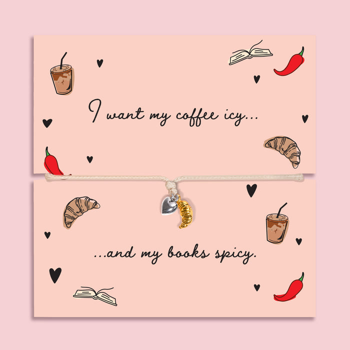 Adjustable book lover bracelet with silver-plated heart charm and gold-tone croissant charm on a peach “I want my coffee icy… and my books spicy” card.