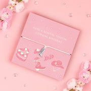 A pink adjustable bracelet featuring a silver-plated cowboy boot charm, displayed on a playful pink backing card with the message "Have a Rootin' Tootin' Cowgirl Birthday" and cowgirl-themed illustrations, including a hat, boots, and cake. Perfect for gifting.