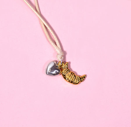 Bracelet with heart and croissant charms on a pink background