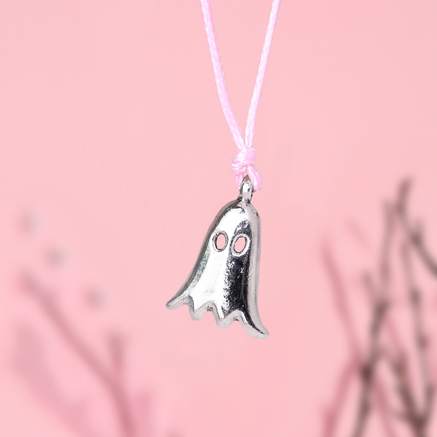 Silver ghost-shaped charm bracelet on a pink cord against a pink background. Cute Autumn jewellery for women for halloween and fall