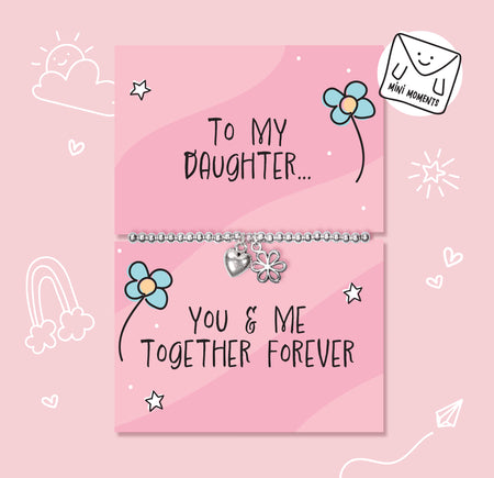 A silver children's bracelet with a heart and flower charm is displayed on a pink gift card that reads 'To My Daughter.