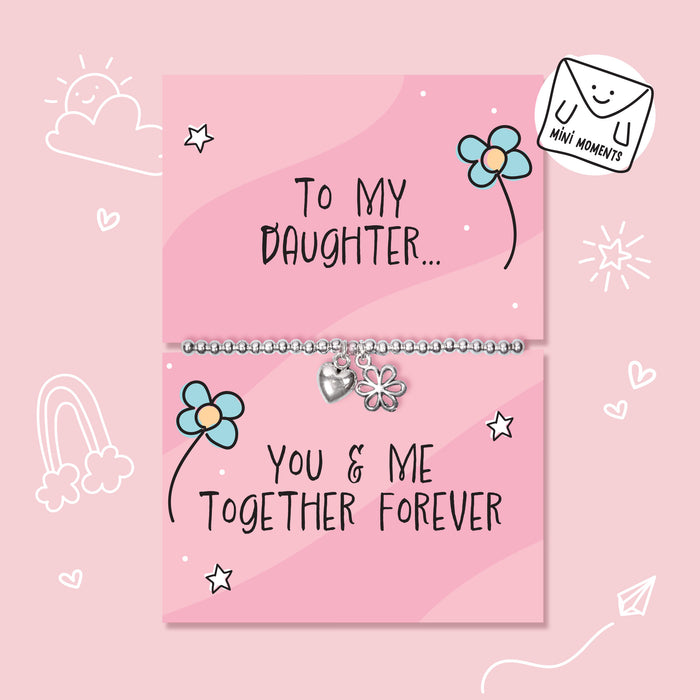 A silver children's bracelet with a heart and flower charm is displayed on a pink gift card that reads 'To My Daughter.