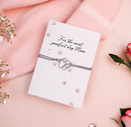 Letterbox Love Dog Mum bracelet with a silver pawprint charm, set on a card with a 'pawfect dog Mum' message and pawprint design. Thoughtful gift for dog lovers, featuring eco-friendly seed paper design.