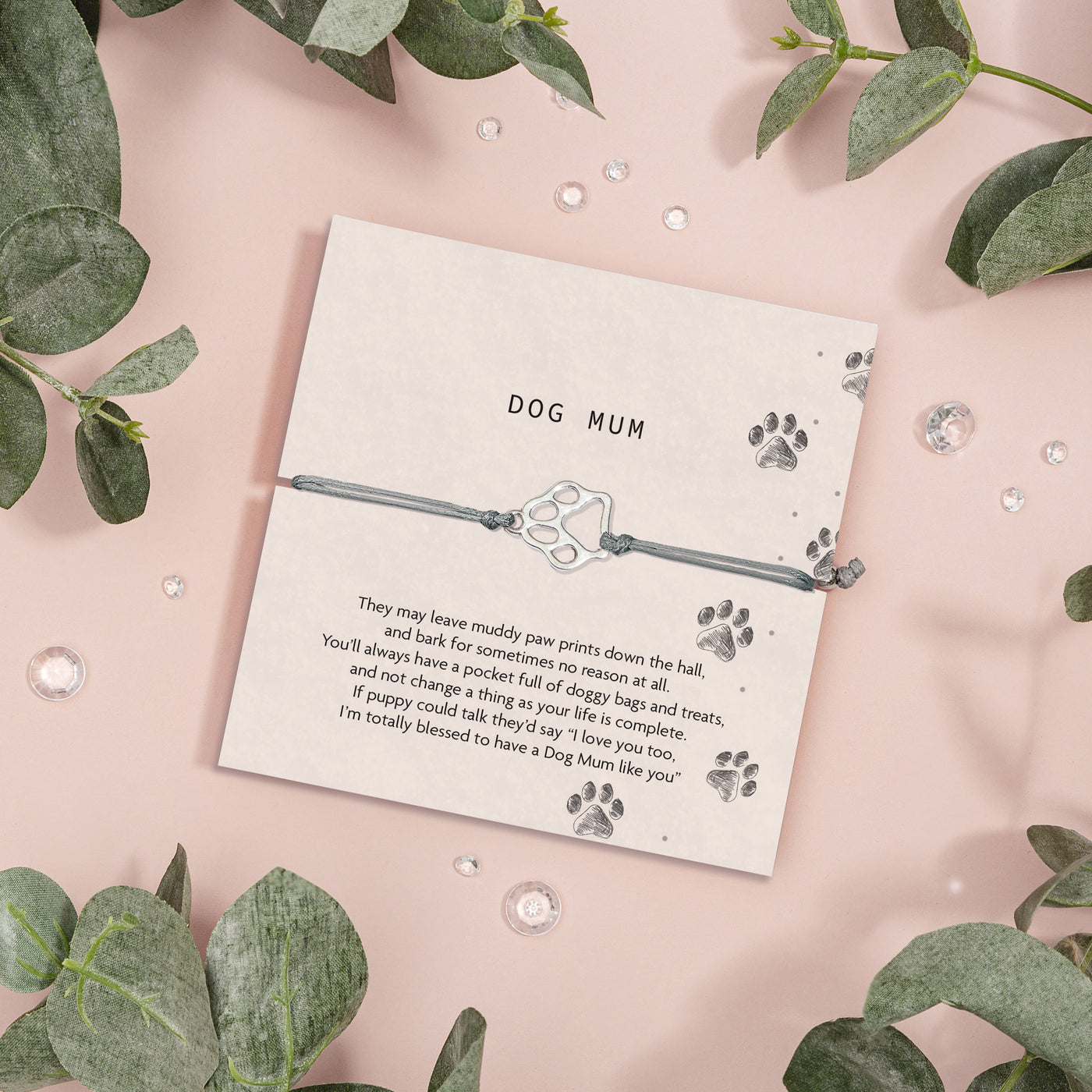 Meaningful card with paw print design and text on a pink background with green leaves. A friendship bracelet with a grey string and cute paw bracelet. A gift for animal lovers.