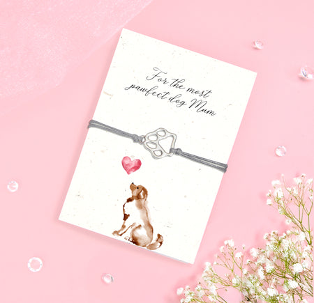 Dog Mum bracelet gift featuring a silver-tone paw print charm on a grey adjustable cord, displayed on a folded seeded card with a sweet dog illustration and the message “For the most pawfect dog Mum.” This eco-friendly jewellery gift is perfect for dog lovers, pet mums, and Mother’s Day. The seeded card can be planted to grow wildflowers, making it a thoughtful and sustainable gift for her. A meaningful keepsake for birthdays, Christmas, or everyday appreciation.