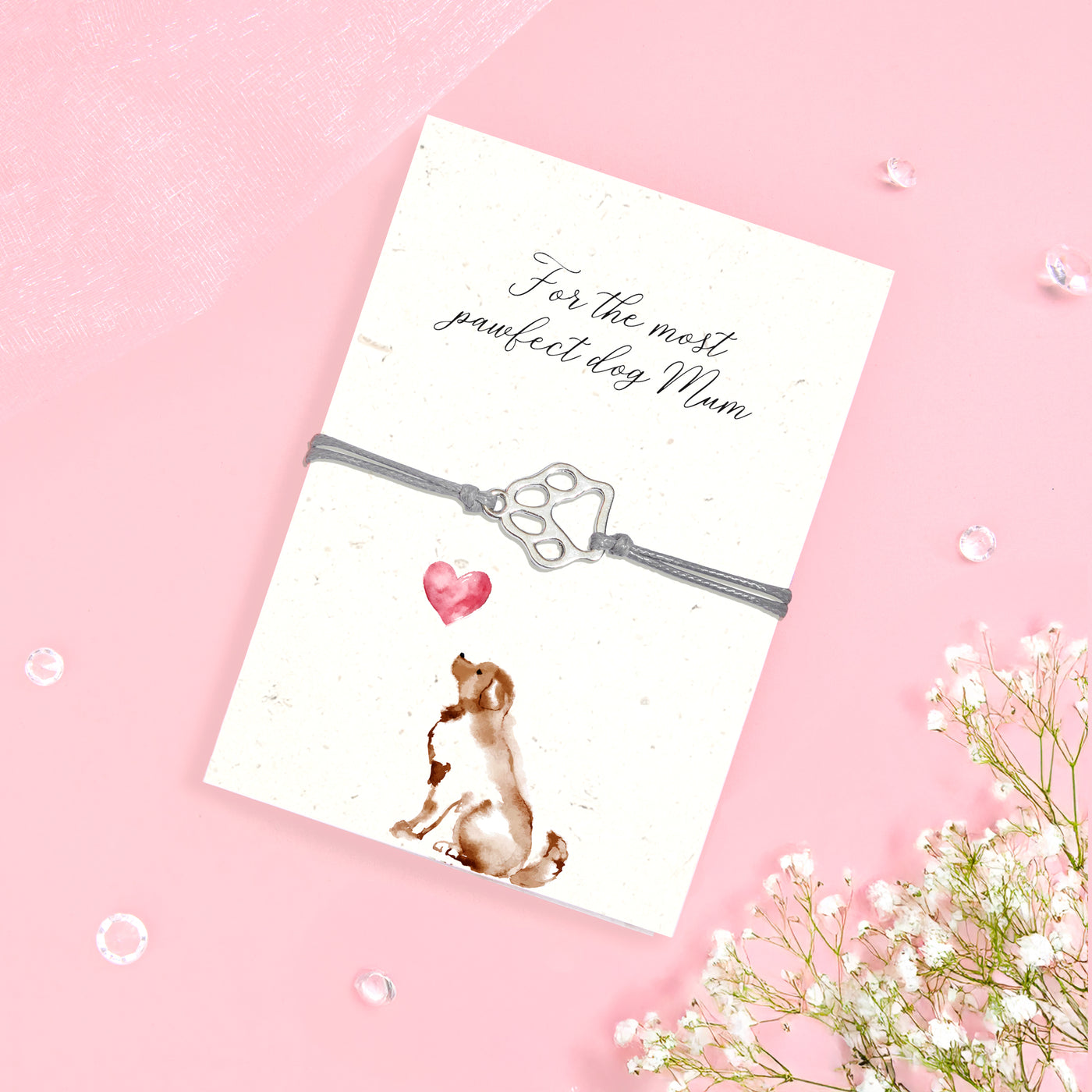 Dog Mum bracelet gift featuring a silver-tone paw print charm on a grey adjustable cord, displayed on a folded seeded card with a sweet dog illustration and the message “For the most pawfect dog Mum.” This eco-friendly jewellery gift is perfect for dog lovers, pet mums, and Mother’s Day. The seeded card can be planted to grow wildflowers, making it a thoughtful and sustainable gift for her. A meaningful keepsake for birthdays, Christmas, or everyday appreciation.