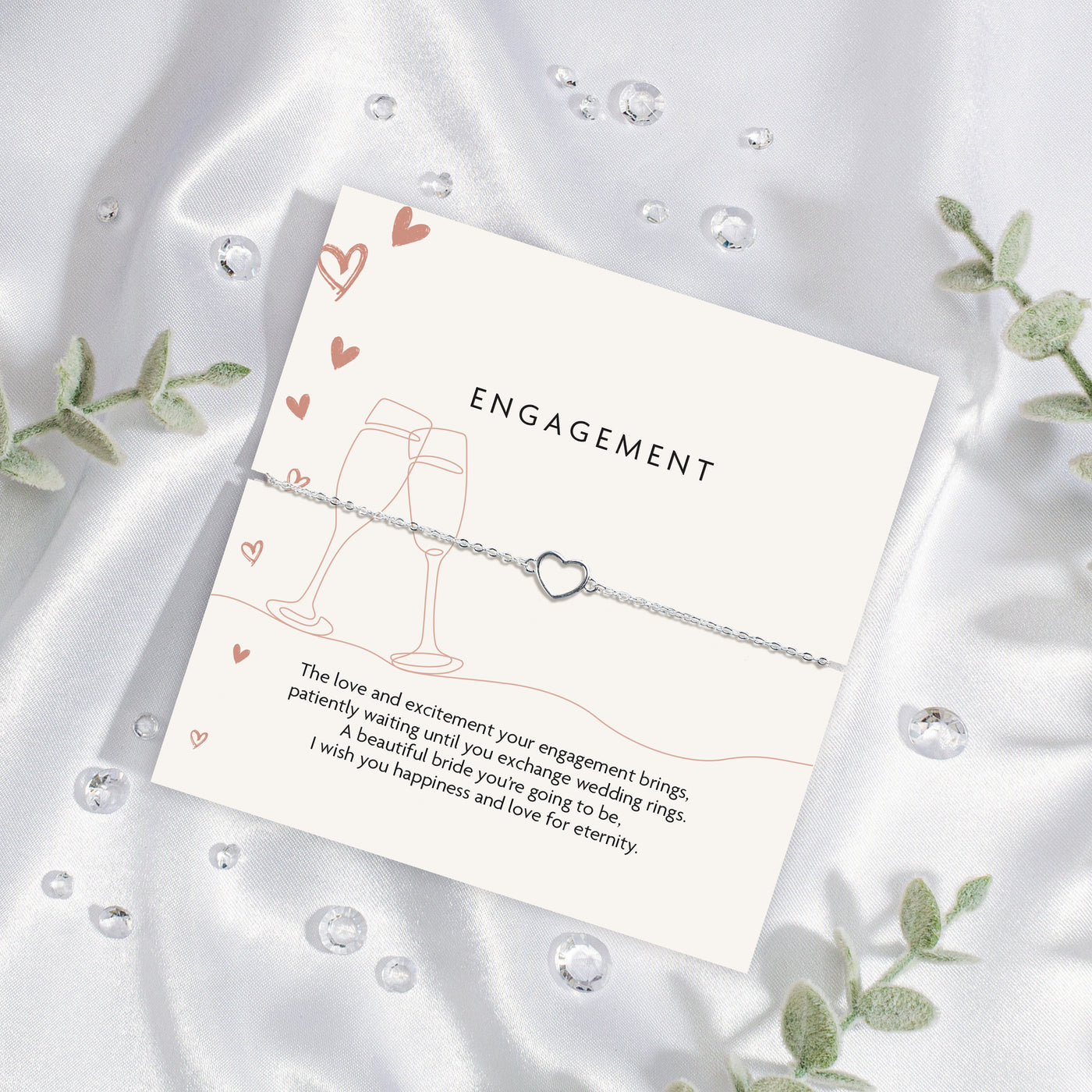 Letterbox Love poem card with brown celebration illustrations and a meaningful poem. Around the card is a silver-plated hollow heart bracelet, an elegant gift for an engagement, with a silk background.