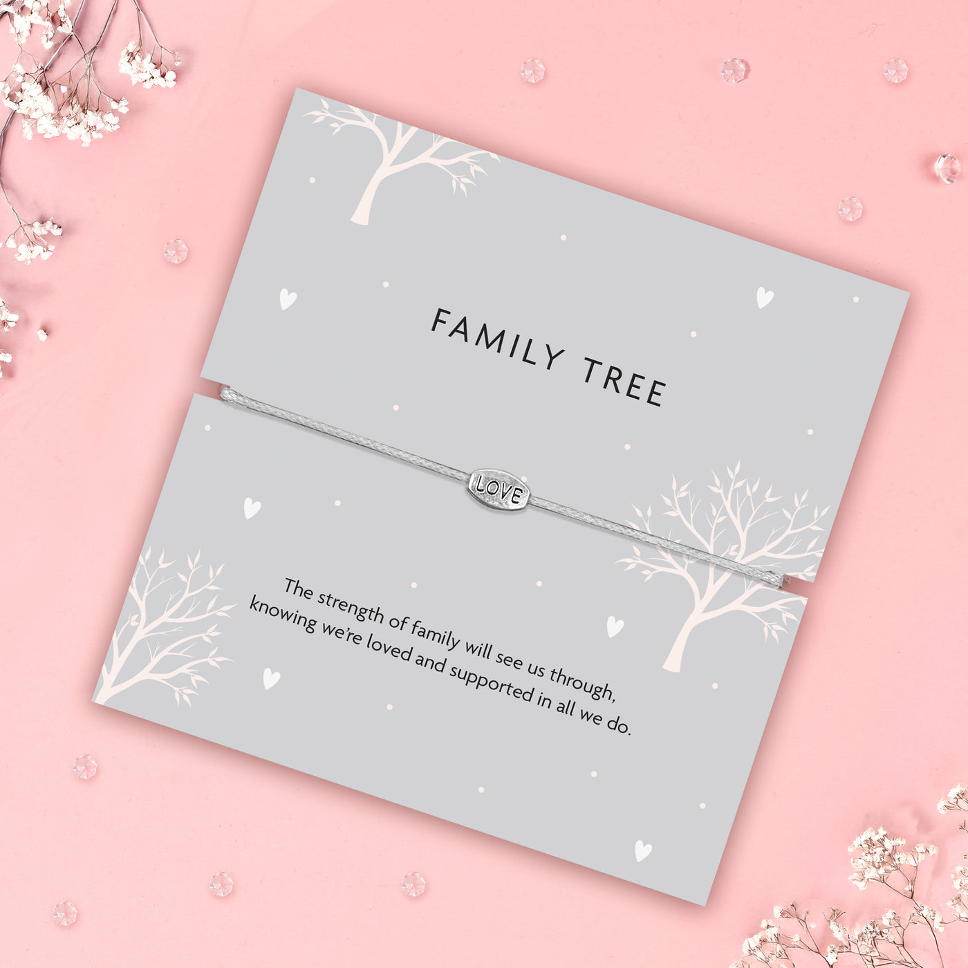 Silver bracelet with 'LOVE' charm on a 'FAMILY TREE' card with text on a pink background.