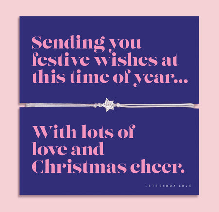 Festive star bracelet featuring a sparkling cubic zirconia star charm on an adjustable cord, presented on a bold navy Christmas card with the message “Sending you festive wishes at this time of year… With lots of love and Christmas cheer.” Includes a soft white pouch for gifting and safekeeping. A thoughtful Christmas jewellery gift, perfect as a stocking filler and Secret Santa present.